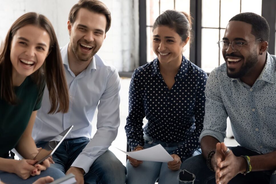 Coach-or-group-leader-telling-funny-story-or-joke-to-laughing-diverse-team