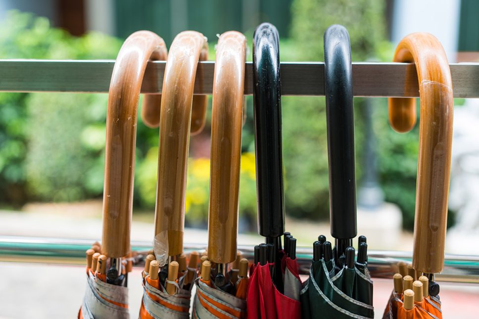 Closed-folding-umbrellas-with-handles-hanging-on-a-rail-